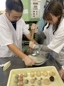 Toshi-san helps Mathilde, one of our former interns, to make mochi. They stand together holding a large stick that is used to pound the rice down.