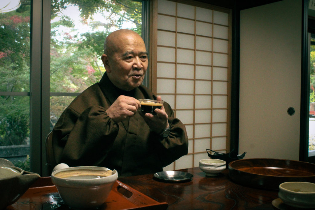 The chief abbot of Shouhouji drinks coffee while smiling.