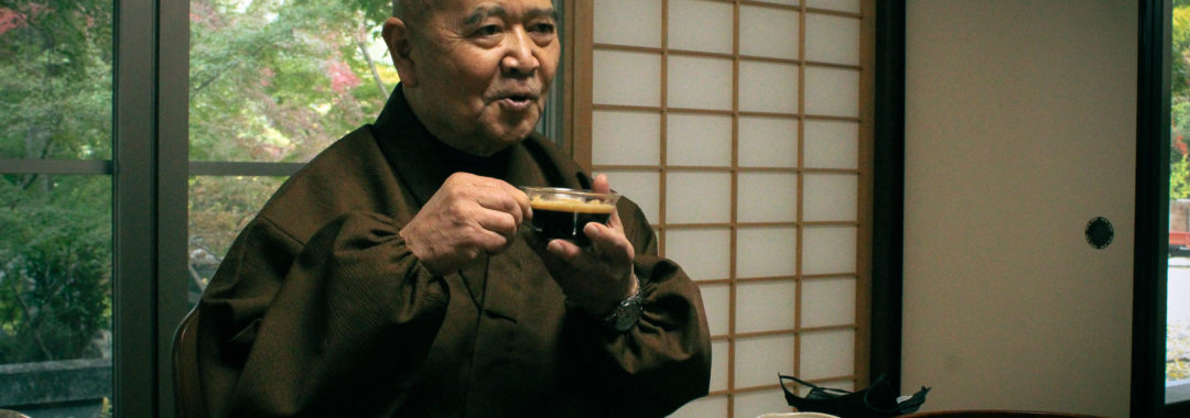The chief abbot of Shouhouji drinks coffee while smiling.
