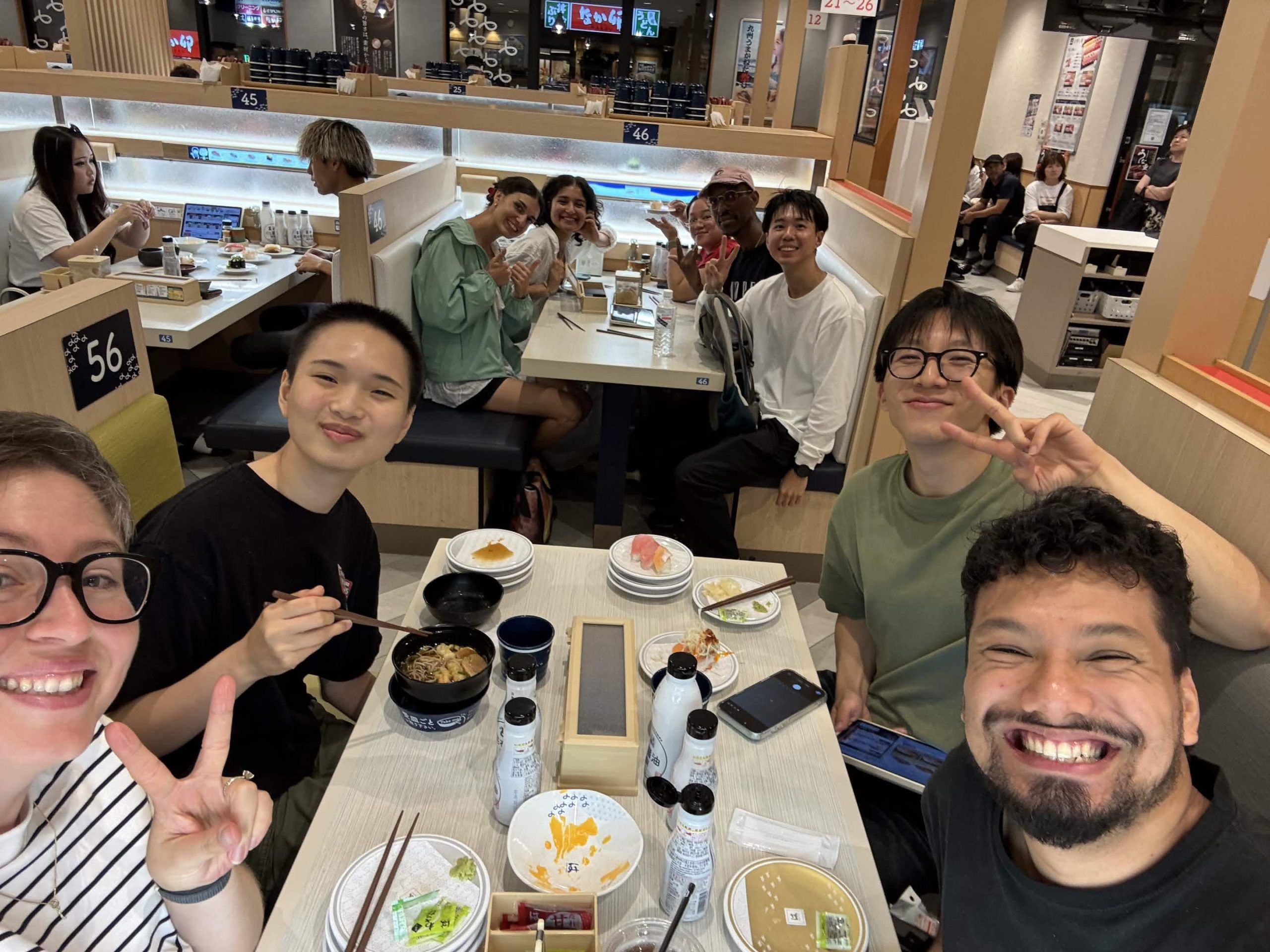 Slot 2 and Slot 3 posed together at two tables eating Hama Sushi
